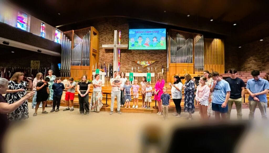 A large group of people near a stage praying
